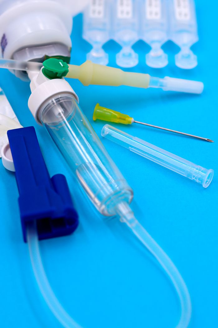 Services Close-up of medical syringes, needles, and tubes on a blue background.