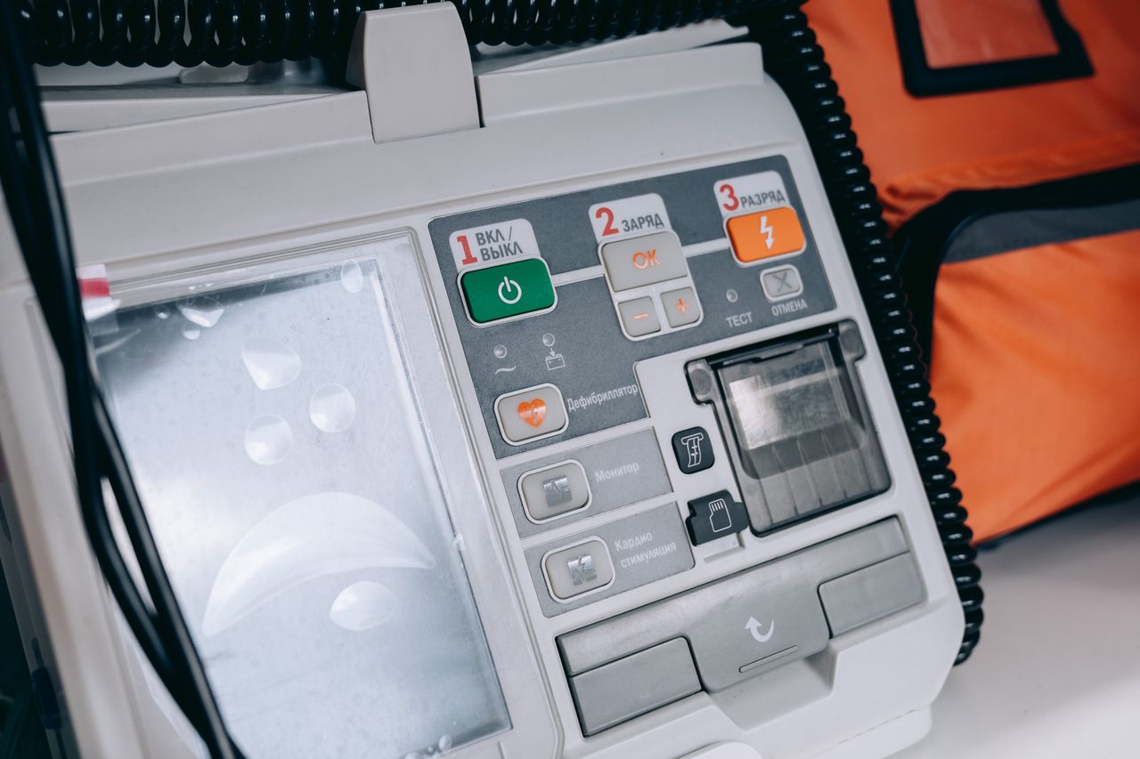 Close-up of a modern medical defibrillator with control buttons and cables.